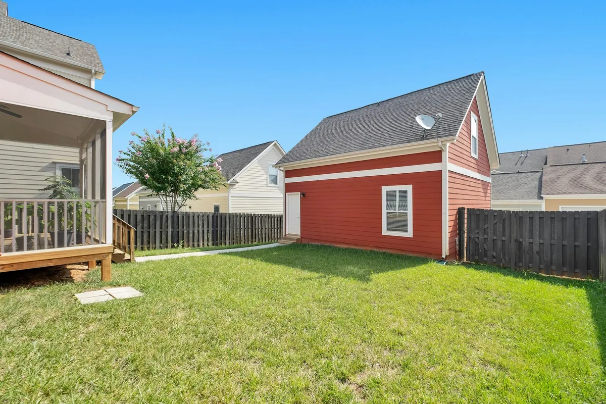 Before: a plain lawn with a dark timber fence, a screened porch on the left and a small red outbuilding.