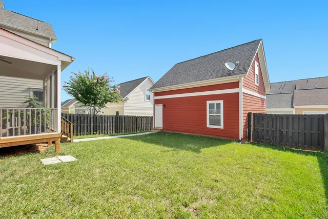 Before: a plain lawn with a dark timber fence, a screened porch on the left and a small red outbuilding.