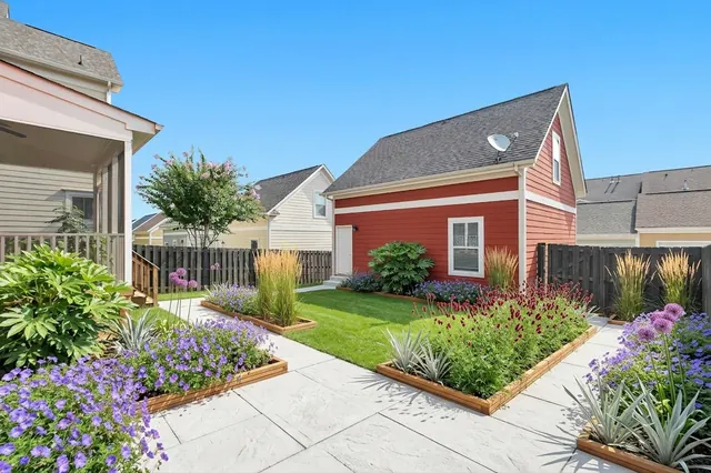 AI generated modern redesign of the same view: a plain lawn with a dark timber fence, a screened porch on the left and a small red outbuilding, replanted.