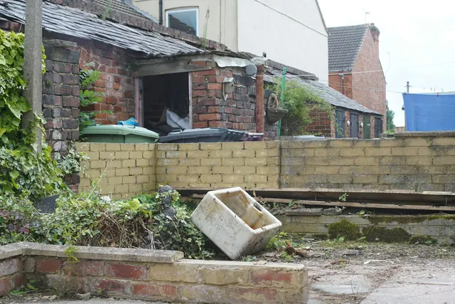 Before: a dilapidated backyard with old brick outbuildings, a low wall, rubble, a discarded sink and weeds.
