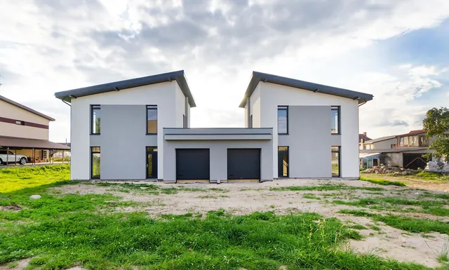 Before: the rear of a new-build pair of houses with garages, a bare sandy plot and patchy new grass in front.