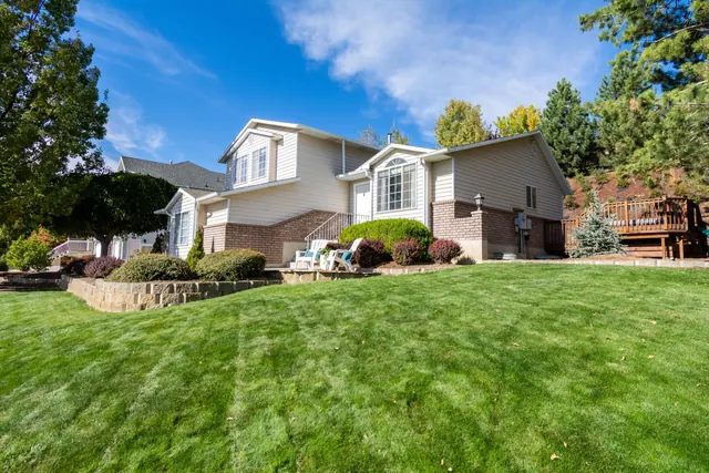 Before: a sloping lawn in front of a split-level house with a low stone retaining wall and shrub beds.